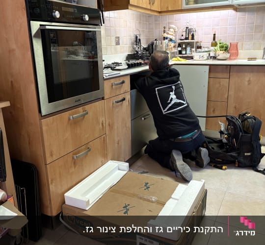 אדם עובד במטבח עם ארגז כלים ומכשירים